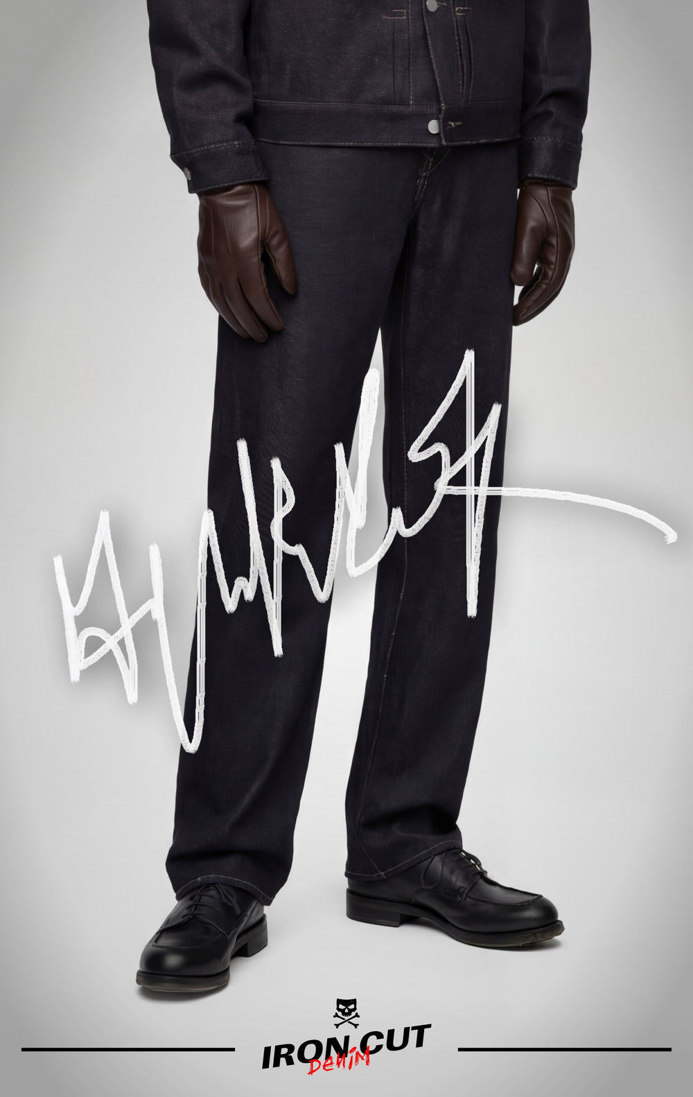 A person wearing IRON CUT black straight-leg jeans with black leather shoes and a matching denim jacket.