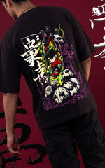 Full-body back view of a model in a black oversized graphic tee and black cargo pants. The image features a "Toxic Waste" theme with large 3D Japanese calligraphy and a warning message about "harmful or dangerous" substances along the side.