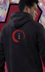 Back view of a black streetwear hoodie featuring a red Enso circle with Japanese calligraphy on a male model, set against a dark red backdrop.