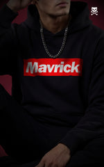 Close-up view of the Mavrick red box logo on a black heavyweight hoodie, accessorized with a silver chain for a modern streetwear aesthetic.