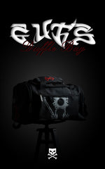 Full view of the black Guts Duffle Bag from Berserk featuring the red Brand of Sacrifice and a silver Dragon Slayer graphic, displayed on a tripod.