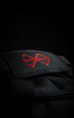 Close-up of the padded handle wrap on the Guts duffle bag featuring a vibrant red embroidered Brand of Sacrifice logo on black heavy-duty canvas.