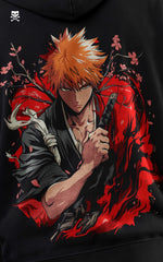 High-definition close-up of the Ichigo Kurosaki anime print on a black hoodie, showcasing the character in his Soul Reaper attire with a red and orange fiery backdrop.