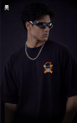 Person wearing a black t-shirt with a graphic design and sunglasses against a dark background