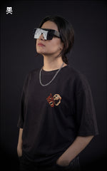 Girl wearing a black t-shirt with a graphic design, standing against a dark background