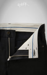 Inside view of the black jeans showing the clean white lining, blue trim, and a sturdy metal zipper.