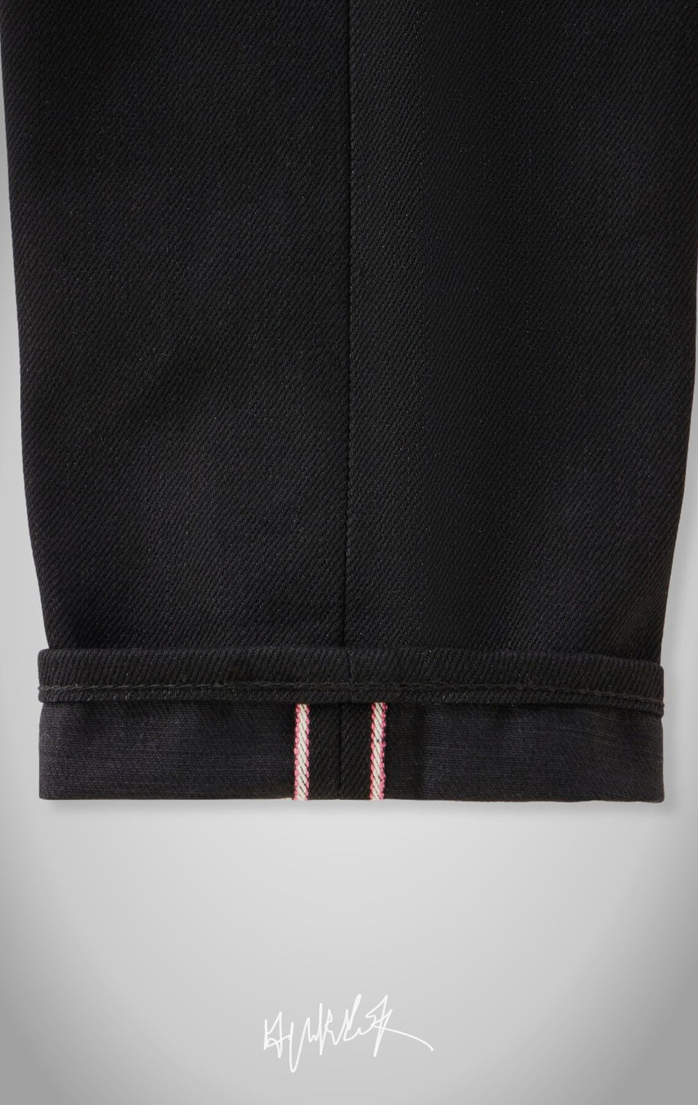 A close-up of the bottom of the jeans cuffed to show the classic red and white selvedge line.