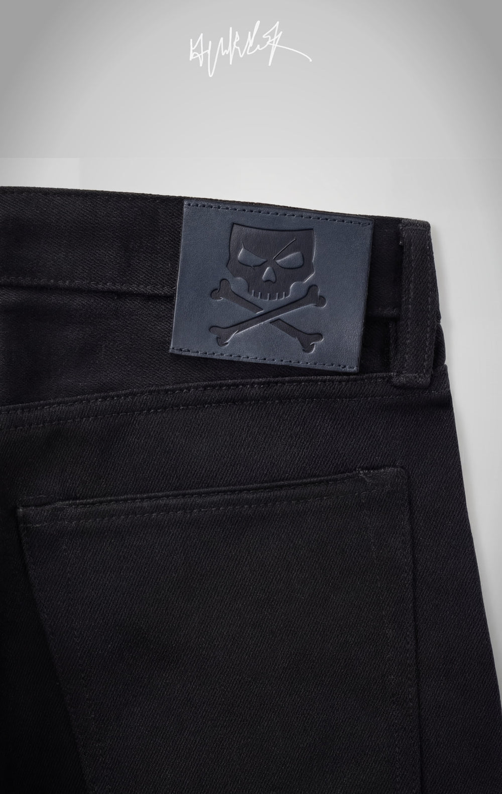 The back of the jeans featuring a signature black leather patch with an embossed skull and crossbones logo.