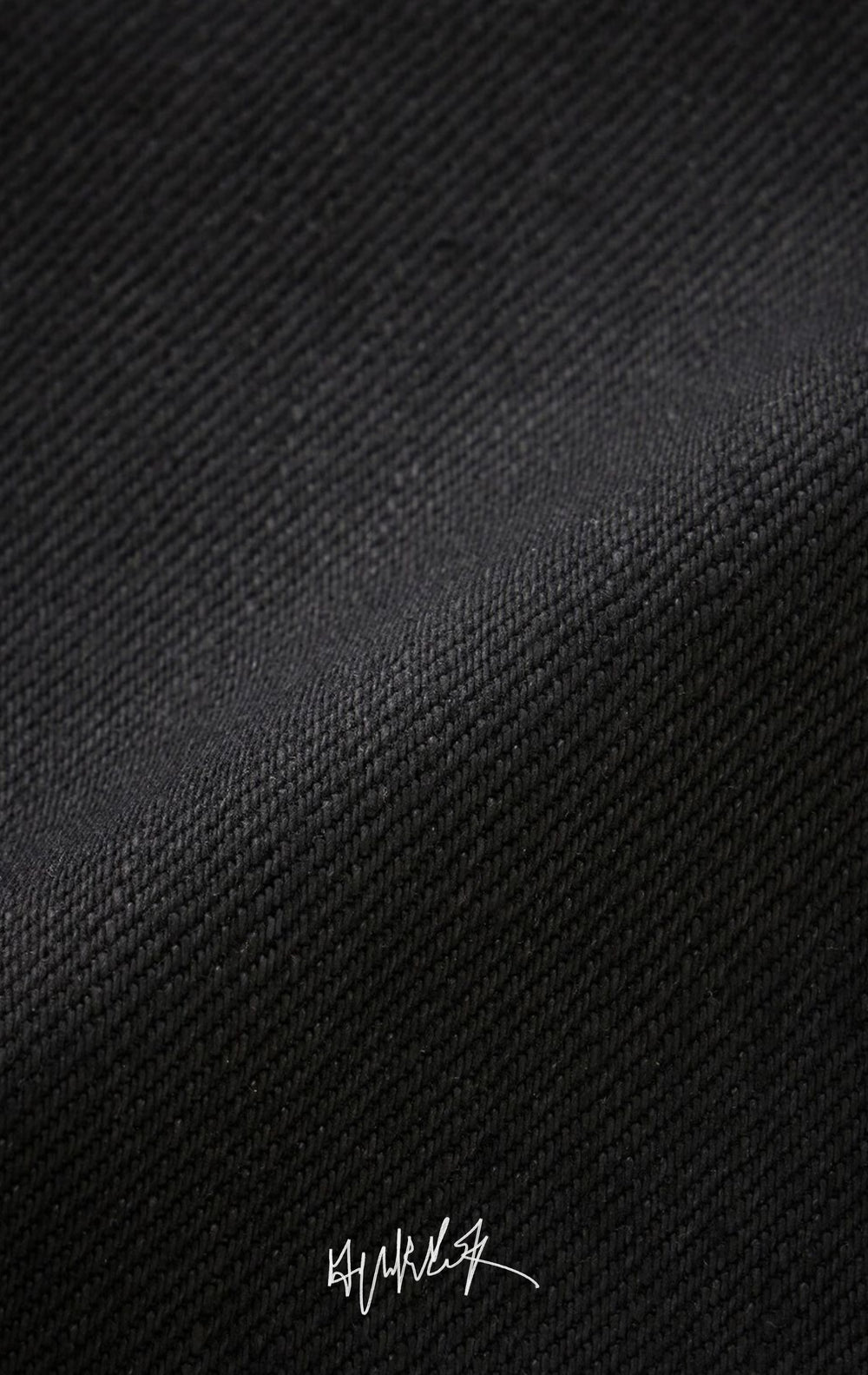 A very close-up shot of the black denim fabric showing its thick, rugged texture.