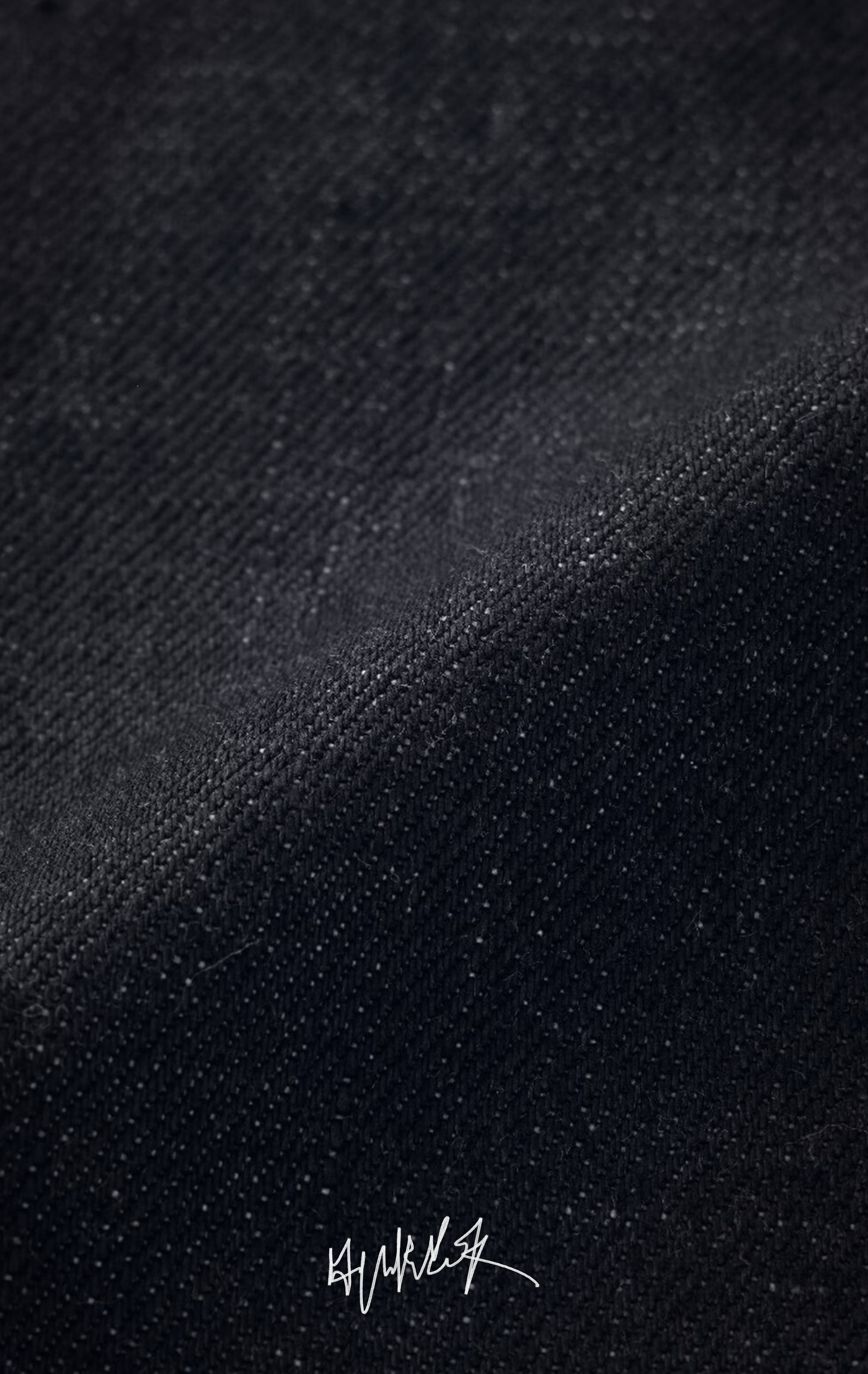 Close-up macro shot showing the texture of dark indigo raw selvedge denim.