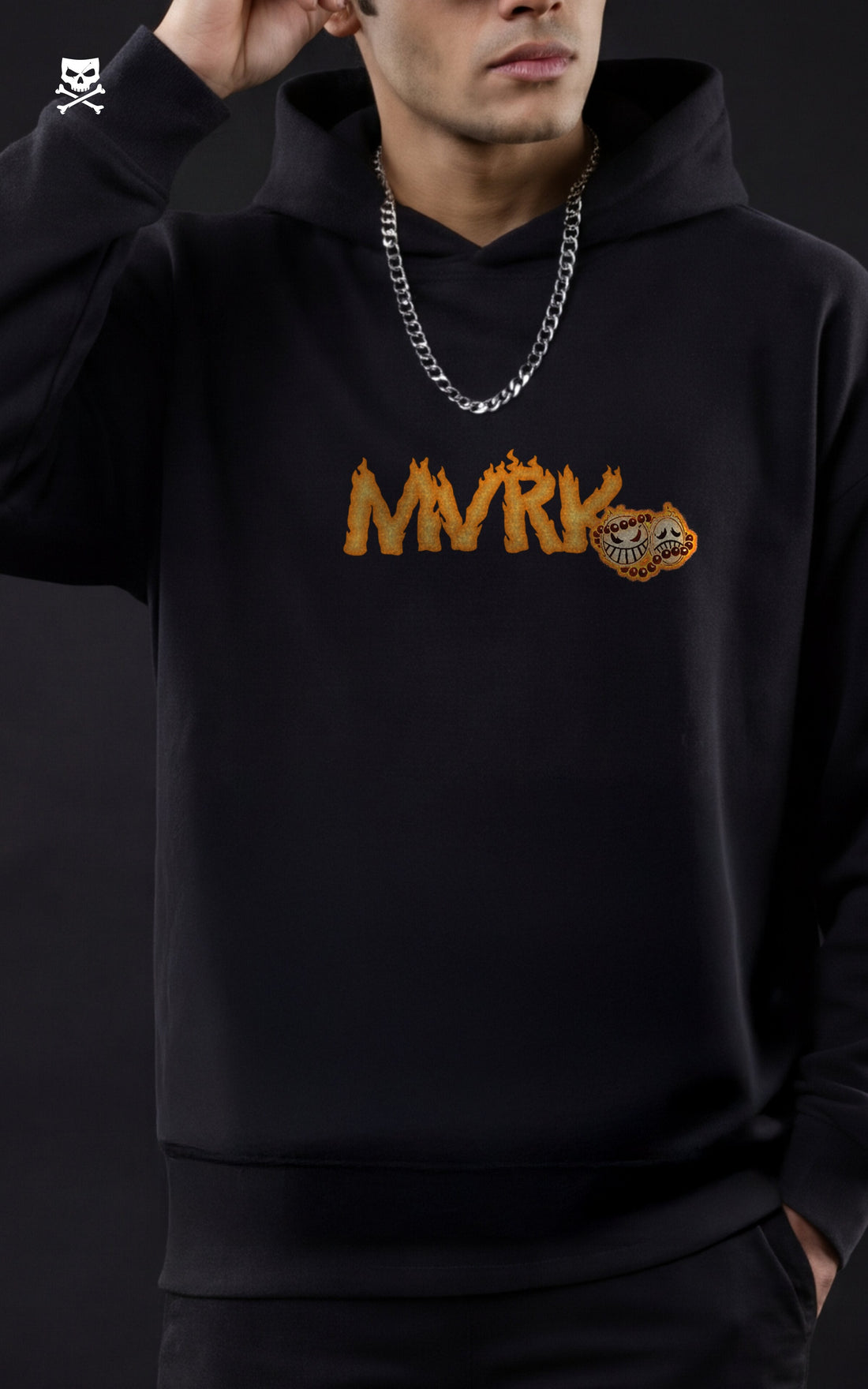 Back view of a man wearing a Mavrick official black streetwear hoodie featuring a large Portgas D. Ace "One Piece" anime graphic with a flame dragon design, posed against a dark studio background with a black stool.