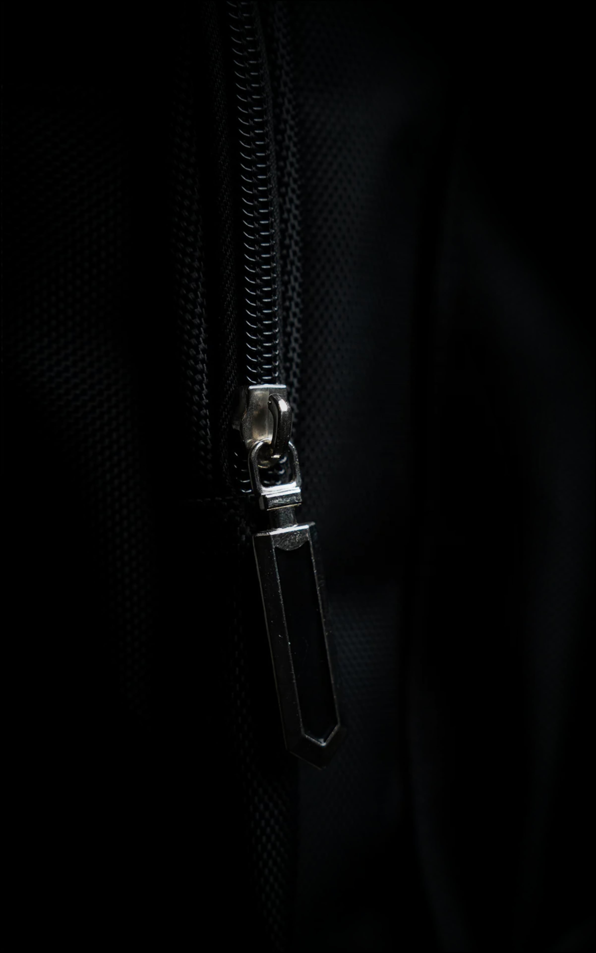 Detailed macro shot of the high-quality metal zipper and sleek geometric pull tab on the black Berserk anime gym bag.
