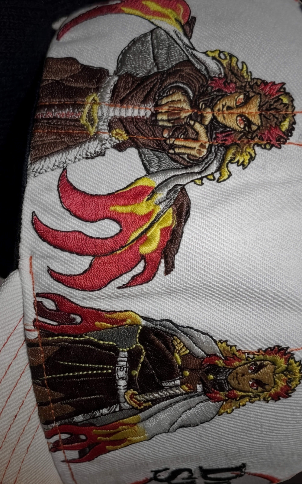 Macro shot of Rengoku character embroidery in multiple action poses on a white streetwear cap.