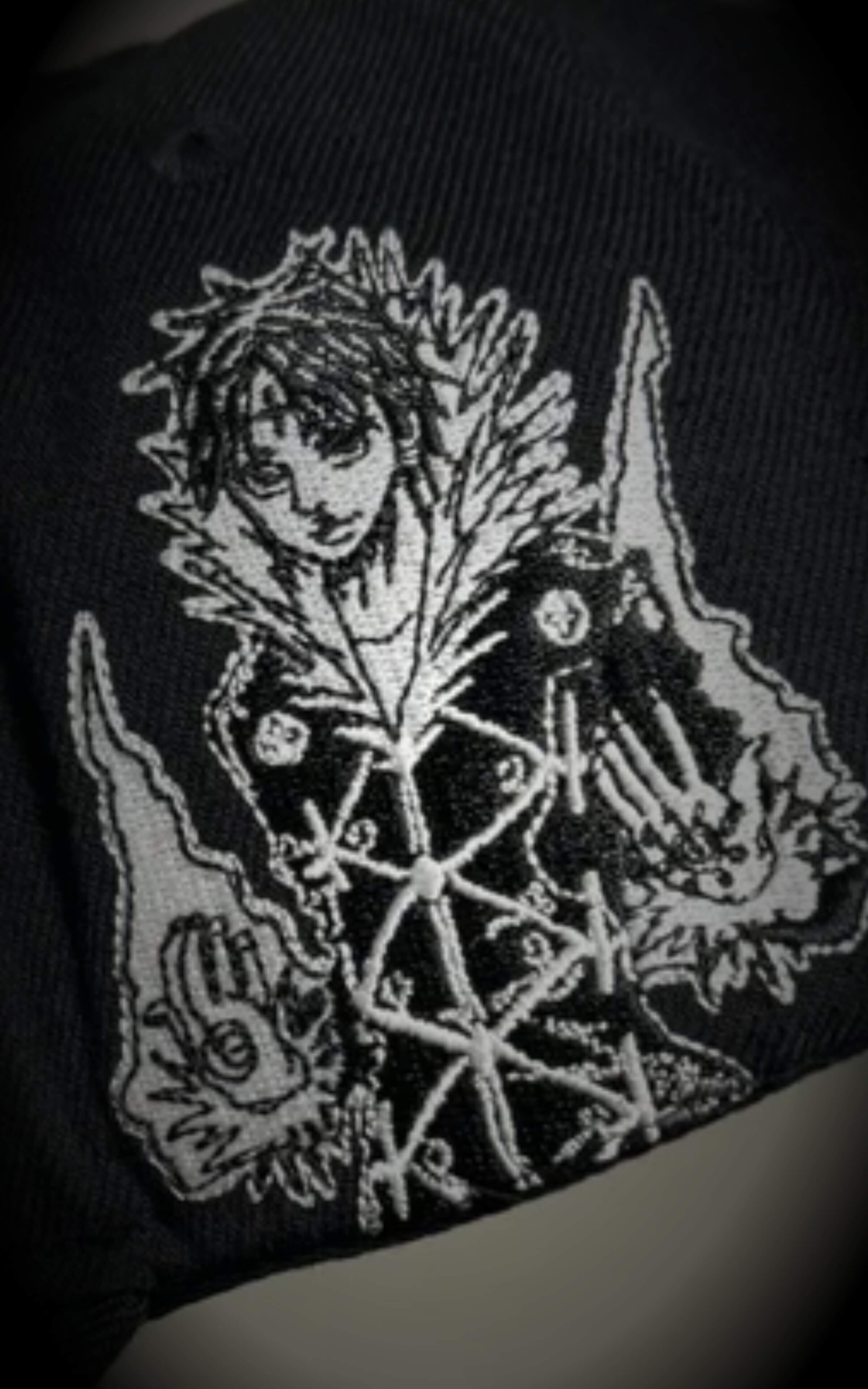 Macro shot of premium gothic embroidery on a black cap, detailing the "CH Los Angeles" text and a skeletal dragon-like motif.