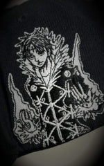 Macro shot of premium gothic embroidery on a black cap, detailing the "CH Los Angeles" text and a skeletal dragon-like motif.