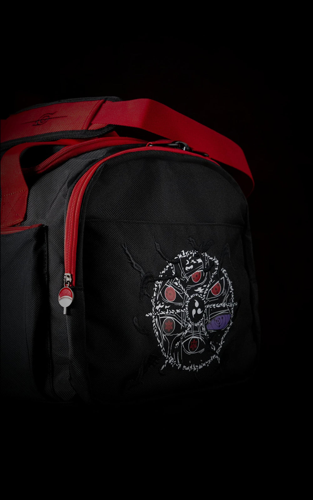 Side view of the Uchiha travel bag showcasing a circular graphic collage of various Mangekyou Sharingan and Rinnegan eyes with a vibrant red shoulder strap.