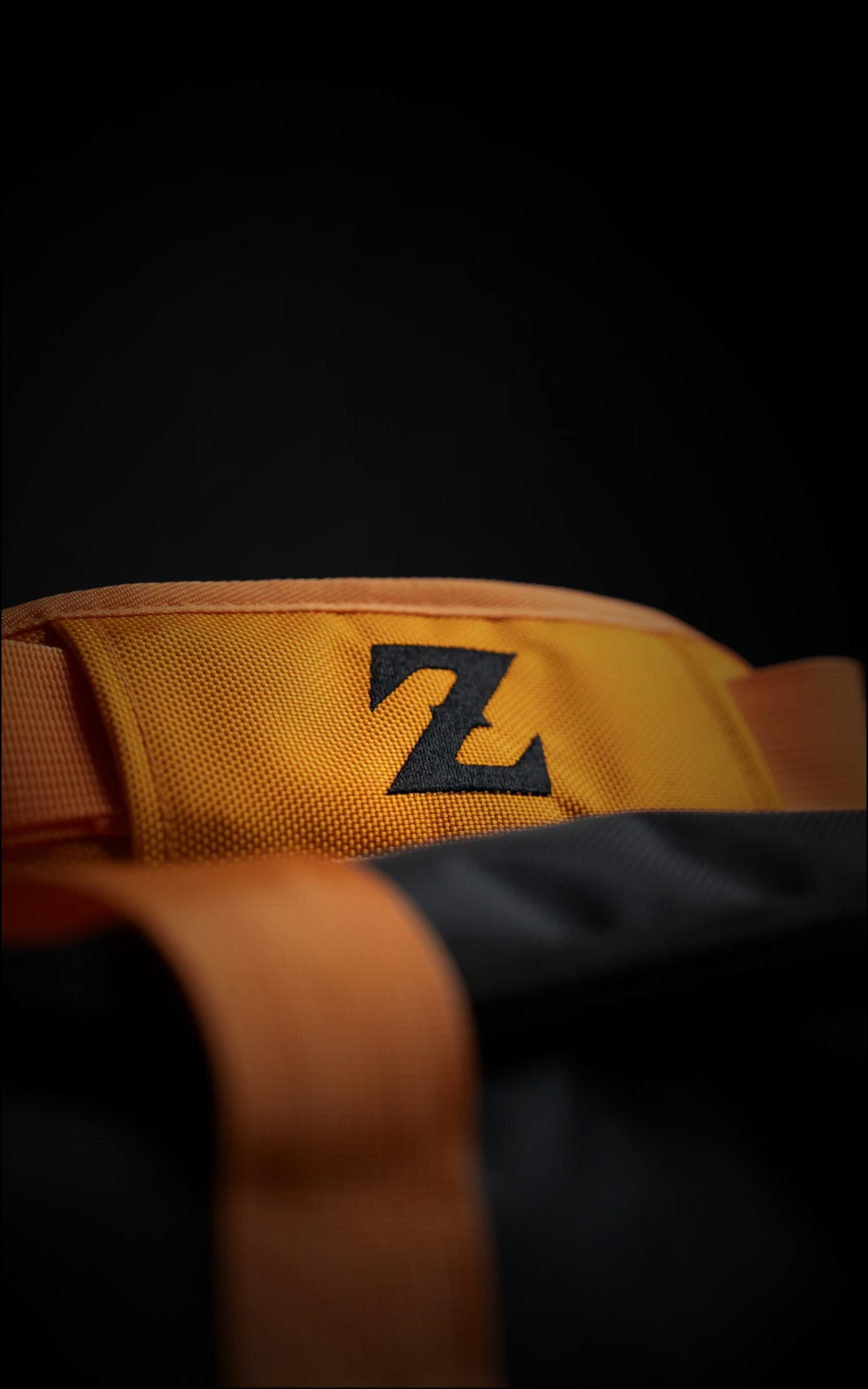 Detailed view of the orange padded handle wrap on the DBZ duffle bag featuring a black embroidered "Z" logo on durable tactical fabric.