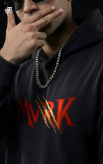Front view portrait of a man wearing a MVRK streetwear hoodie with a flaming chest logo and Shanks' Jolly Roger detail, accessorized with a silver chain and sunglasses.