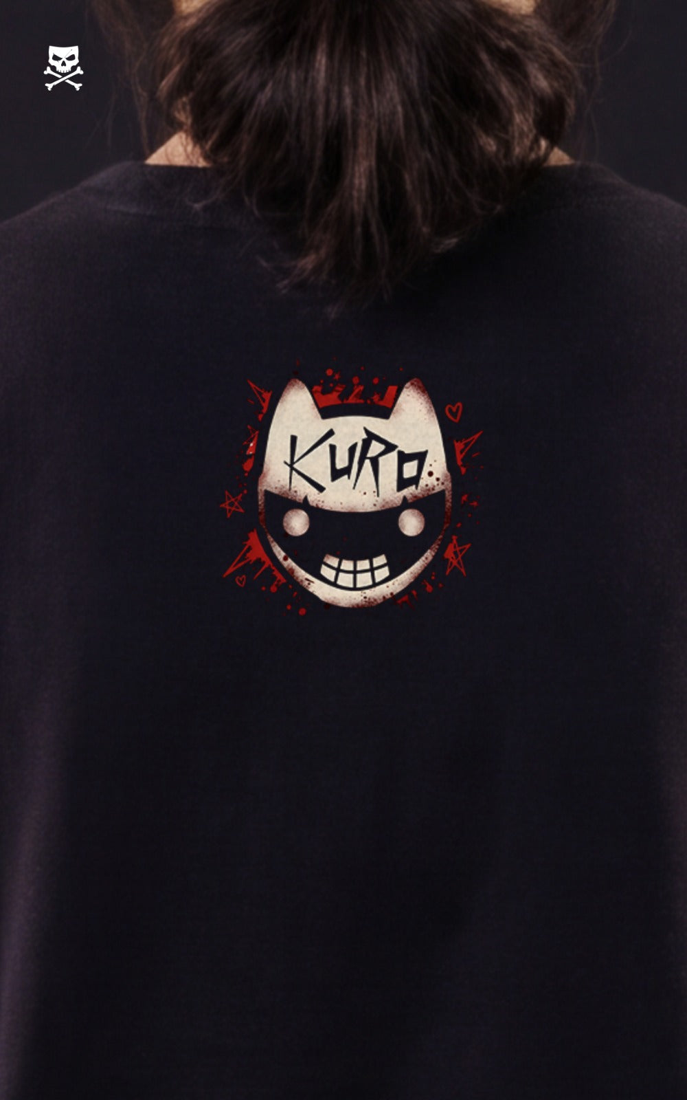 The back of a black t-shirt showing a small, circular graphic of a white cat-like mask with the word "KURO" written on its forehead, surrounded by red splatters.