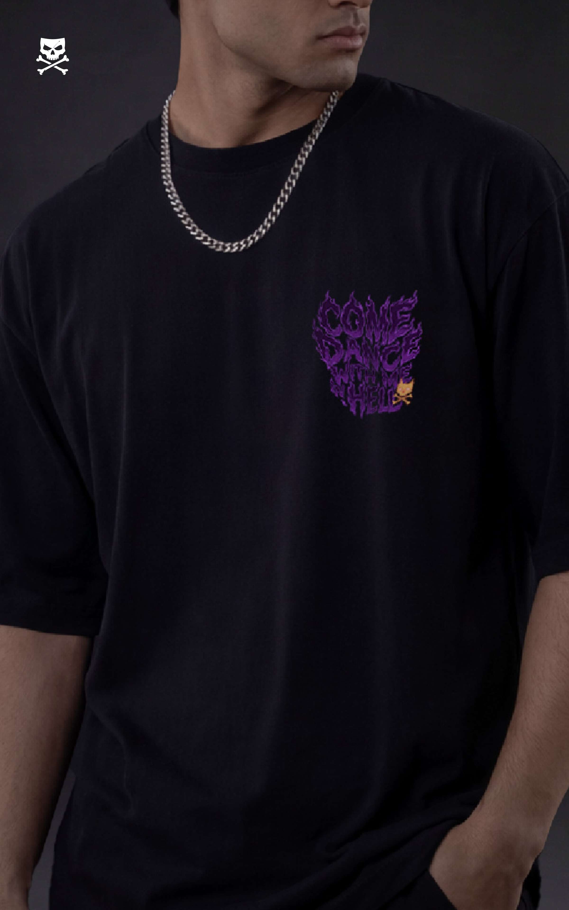 Person wearing a black t-shirt with a purple graphic design of "Come Dance with me in Hell" on a dark background