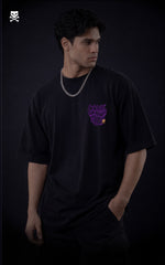 Person wearing a black t-shirt with a purple graphic design of "Come Dance with me in Hell" on a dark background